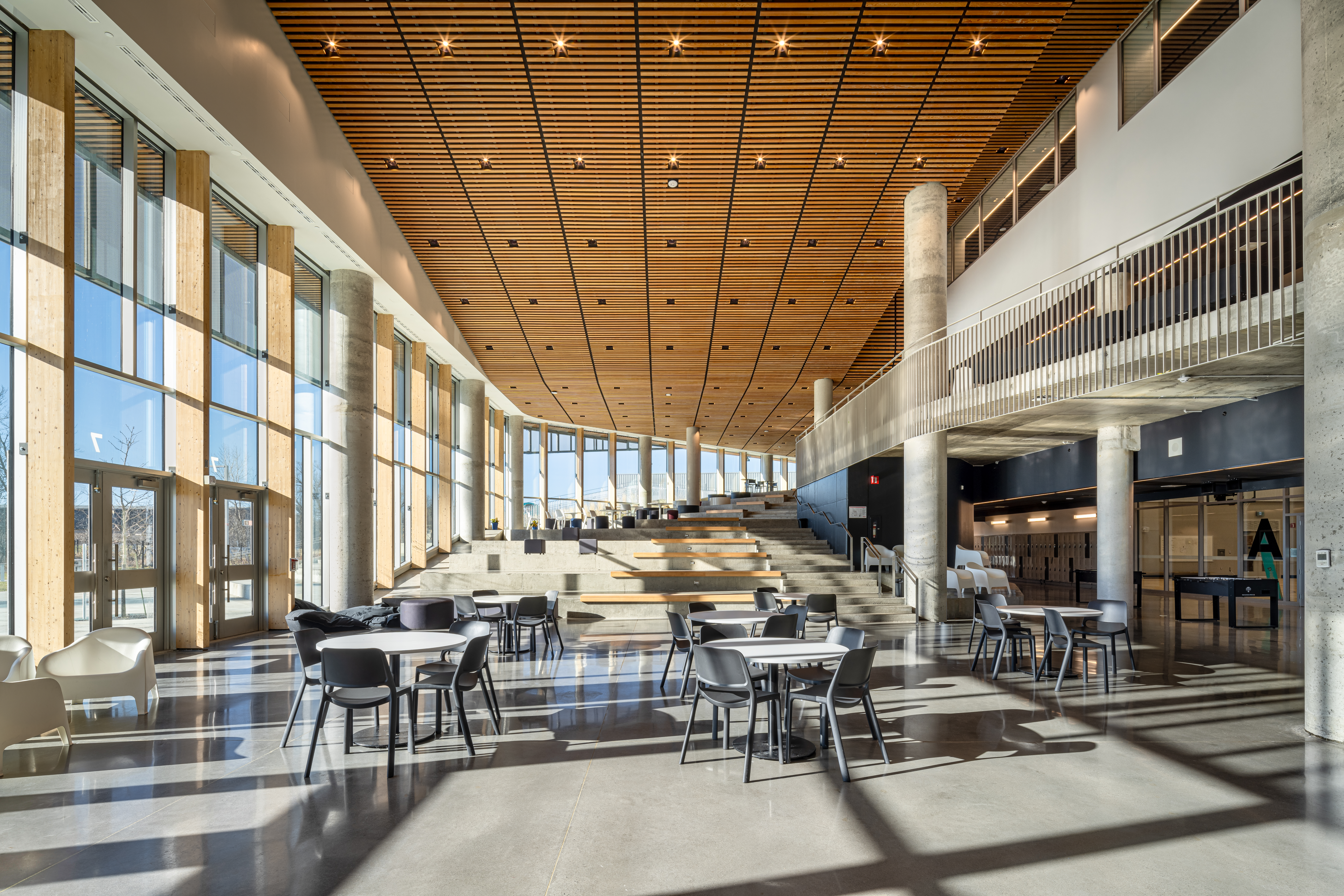 A public usage space at Mirabel High School building exterior using a custom wood LINE:Form Linear Planks system